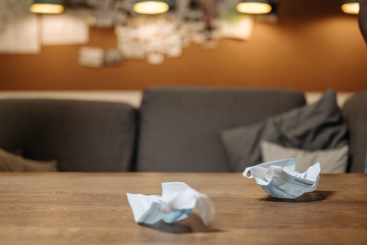 Close-up of unused face masks on a wooden table inside a cozy room.